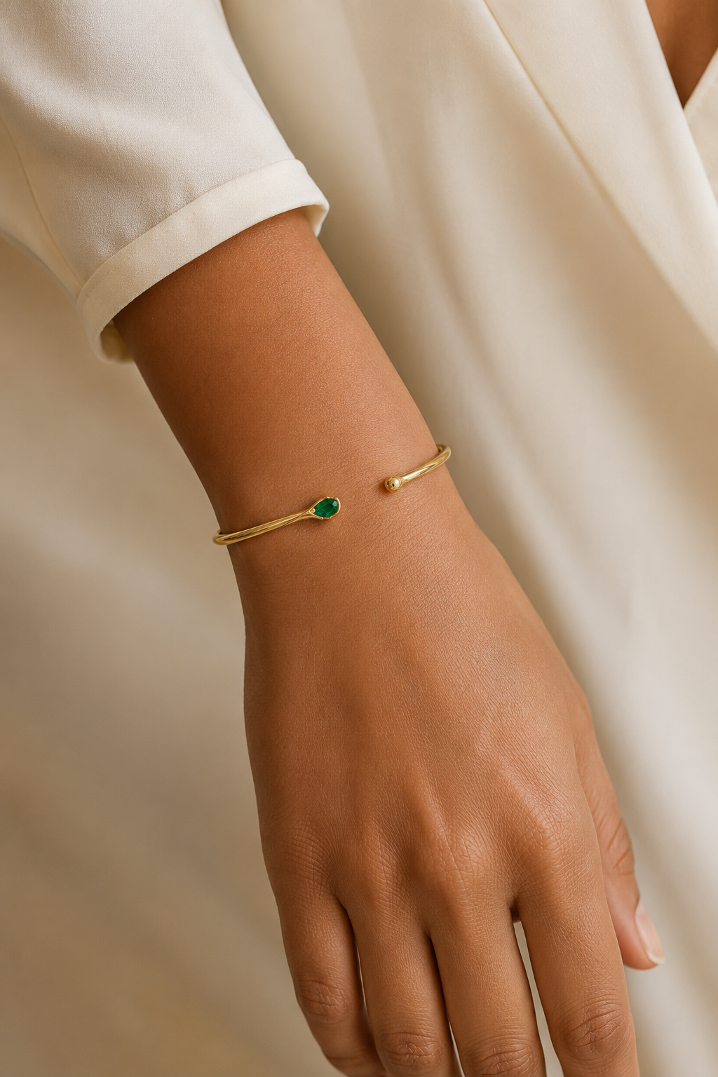 Adult woman wearing Veil Emerald Whisper Bangle — 14k Gold at approximate scale with modest ivory styling