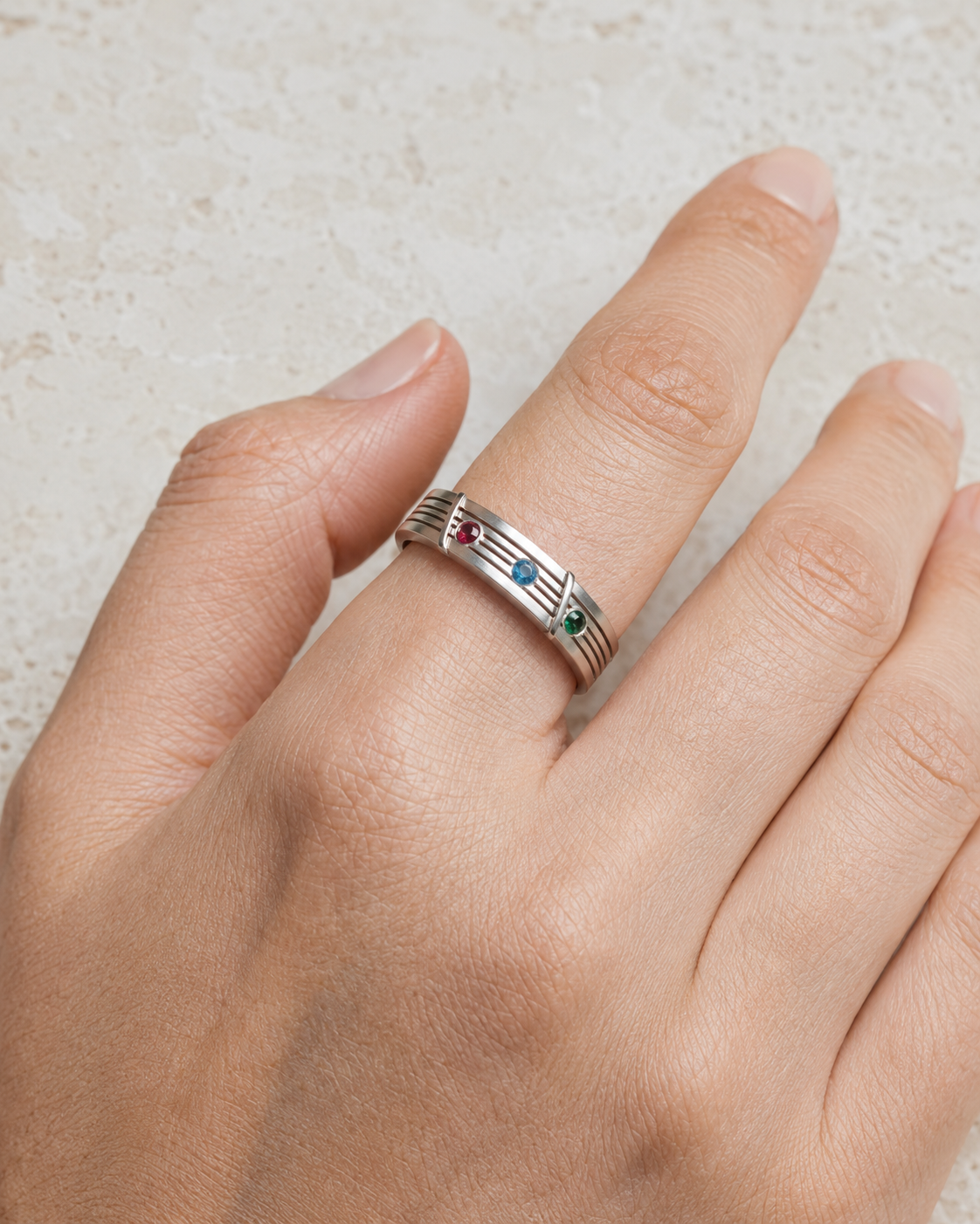 Forgemier Orbit Tactile Band in sterling silver with captive ruby aquamarine and emerald, shown worn to scale